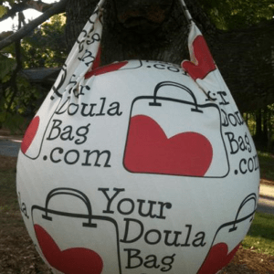 A custom logo bag hanging from a tree with the words doula your doula bag.