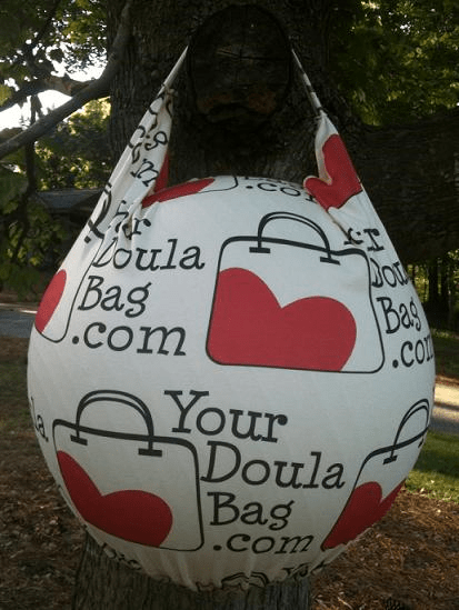 A custom logo bag hanging from a tree with the words doula your doula bag.