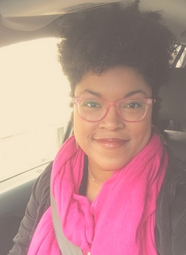 Deidre Medina wearing glasses and a pink scarf in a car.