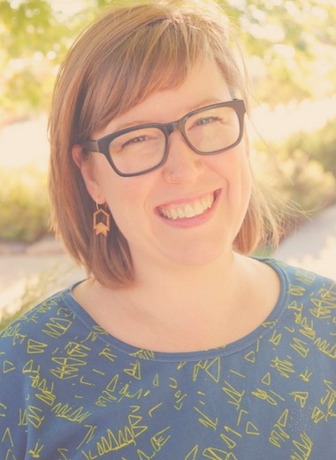 Emily Landry, a smiling woman wearing glasses and a blue shirt.