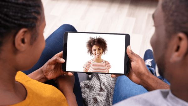 A couple holding a tablet during a virtual doula video call.