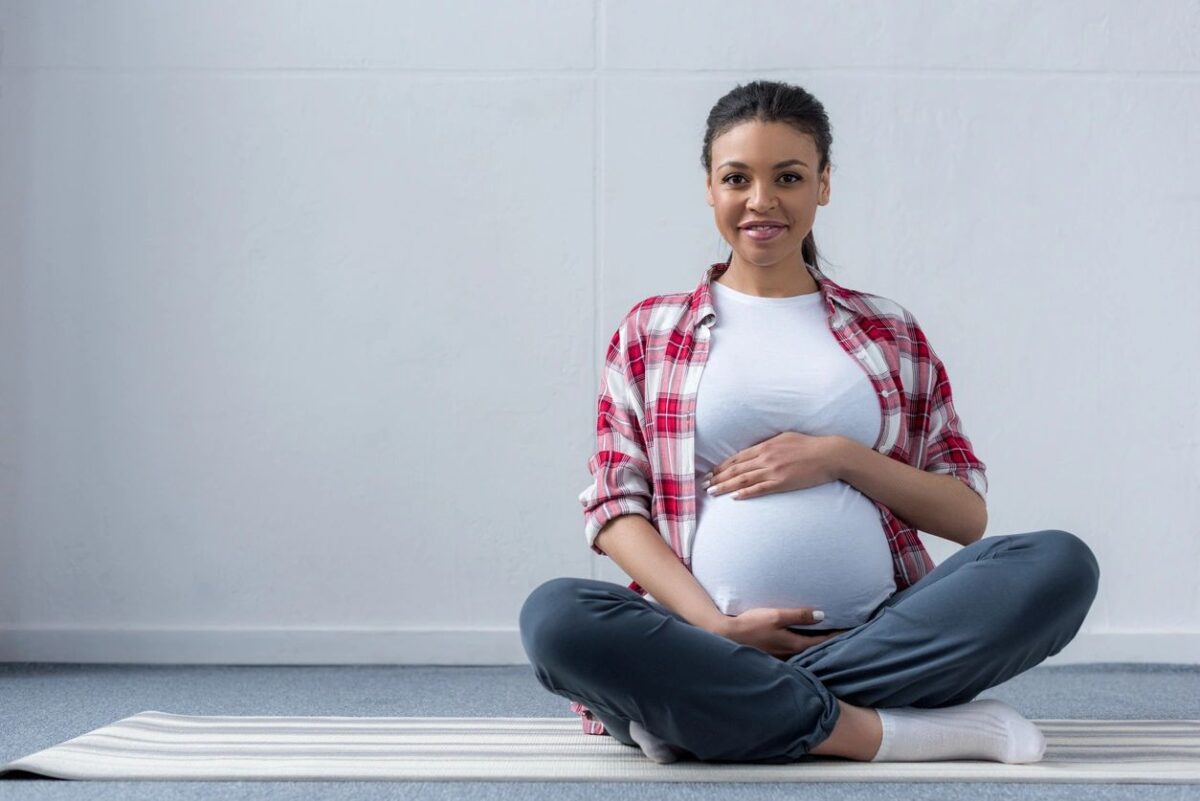 A pregnant woman sitting on a yoga mat.