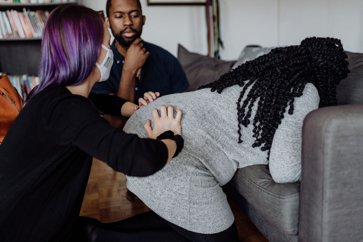 Doula s showing a male partner how to do the double hip squeeze