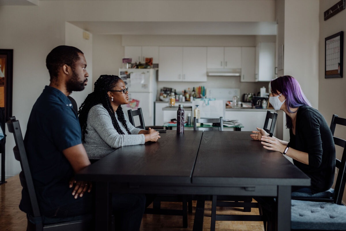 A doula sits at the dining room table with two clients working on a birth plan.